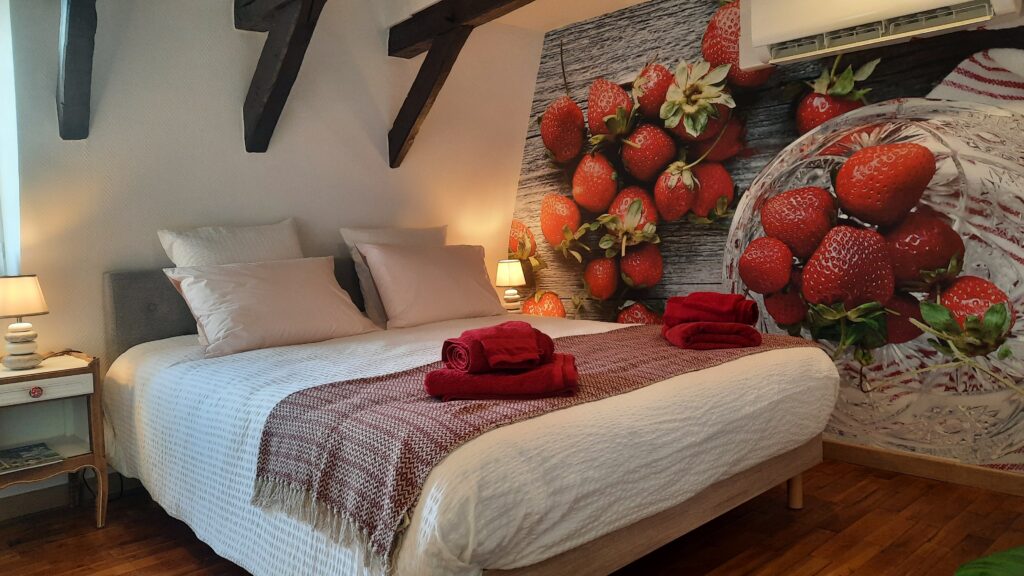 Vue du lit de la chambre Fraise avec la tapisserie représentant des fraises dans une coupelle et étalées sur une table