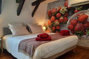 Vue du lit de la chambre Fraise avec la tapisserie représentant des fraises dans une coupelle et étalées sur une table