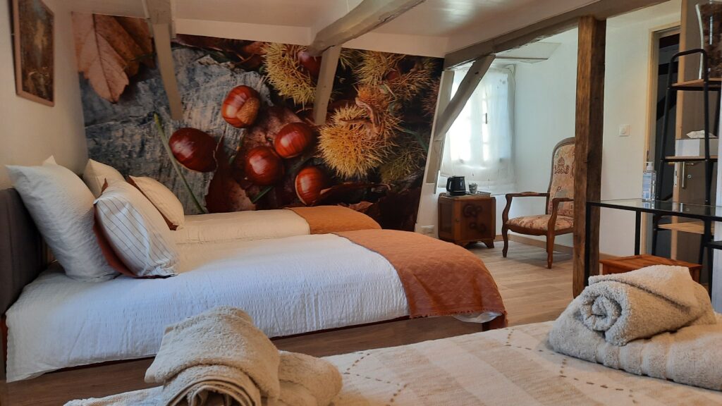 Vue du lit de la chambre Châtaigne avec la tapisserie représentant des châtaignes , certaines dans leur bogue.