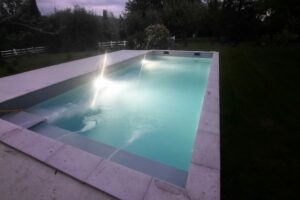 Piscine en eau vue de nuit avec spots allumés